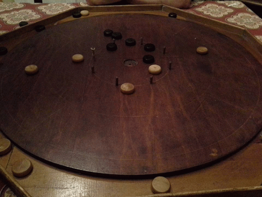 vintage crokinole board - wooden - with wooden checkers on it